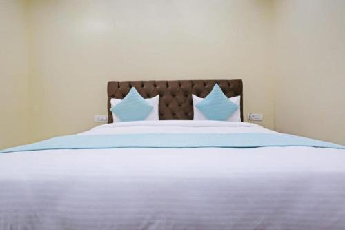 Hotel Mannat at Paschim Vihar في نيودلهي: سرير به شراشف ووسائد زرقاء وبيضاء