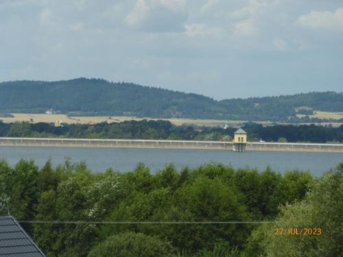 un puente sobre un lago con árboles y una montaña en Dom Nad Zalewem Sosnówka, en Sosnówka