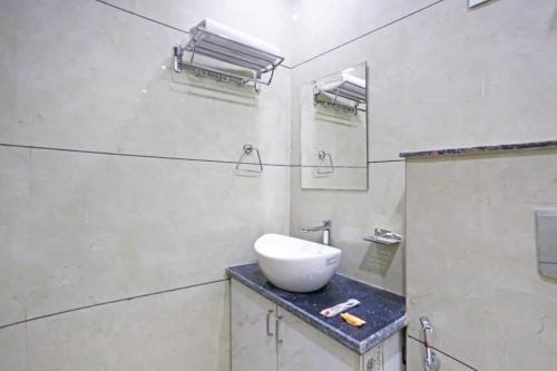 uma casa de banho branca com um lavatório e um espelho em Hotel Mannat at Paschim Vihar em Nova Deli