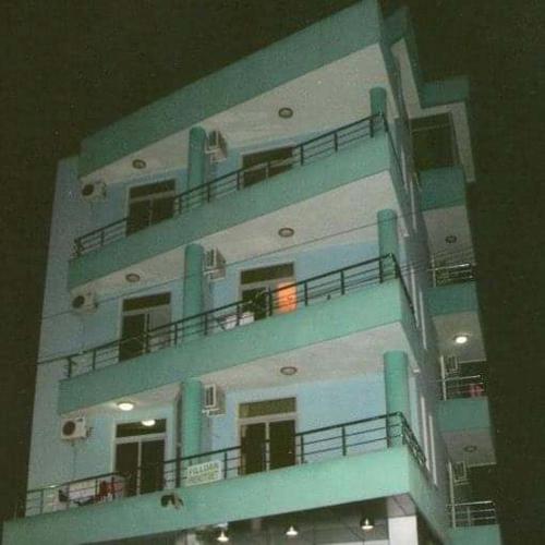um edifício com varandas azuis e um edifício com luzes em REZIDENCA GJELI em Elbasani