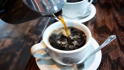 uma pessoa está derramando café em uma xícara em uma mesa em REZIDENCA GJELI em Elbasani