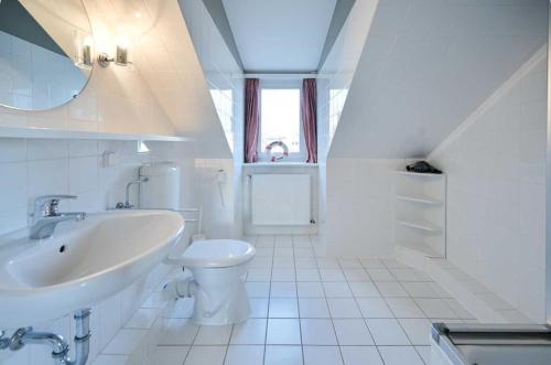 een witte badkamer met een wastafel en een toilet bij Jule - Sonnenhof 9 in Kellenhusen