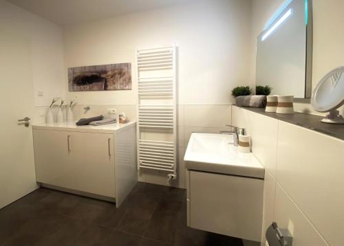 ein weißes Badezimmer mit einem Waschbecken und einem Spiegel in der Unterkunft Sonnenweg 48 - DIEMELBRISE in Heringhausen