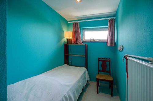 ein blaues Schlafzimmer mit einem Bett und einem Stuhl in der Unterkunft Emil - Sonnenhof 1 in Kellenhusen