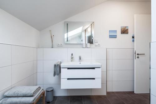 a white bathroom with a sink and a mirror at Casa Báltica Haffkrug in Haffkrug