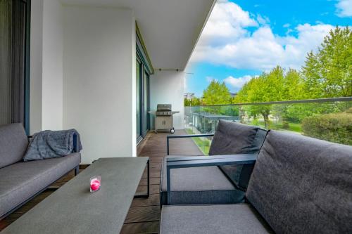 a balcony with a couch and a table and a view at Napfény Resort by HelloBalatonlelle in Balatonlelle