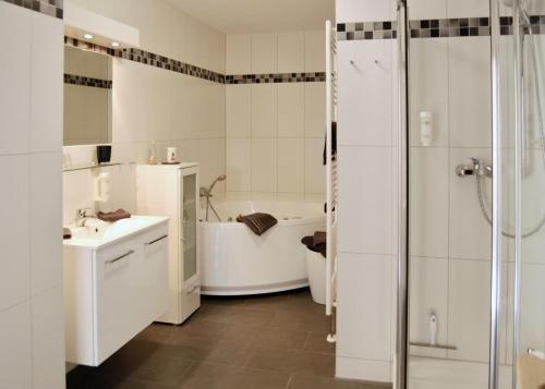 La salle de bains est pourvue d'une baignoire, d'un lavabo et d'une douche. dans l'établissement Leuchtturm 4, à Großenbrode