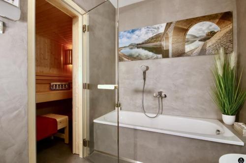 a bathroom with a bath tub with a painting on the wall at Haus Luce - Sonnenweg 13 in Heringhausen