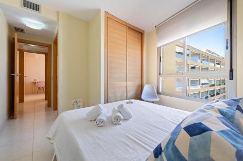 a bedroom with a white bed with a large window at Alea Rentals - Maldivas in La Pineda