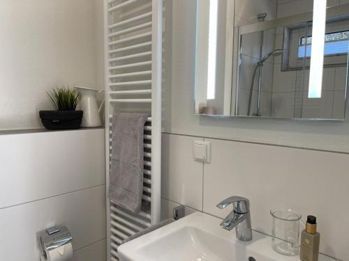 uma casa de banho branca com um lavatório e um espelho em Diemelblick 12 - LENI em Heringhausen