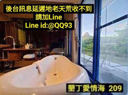 a bathroom with a tub in a room with a window at 墾丁愛情海民宿 in Kenting