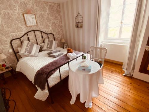 a bedroom with a bed and a table with a teddy bear on it at Les Iris Chambres d’hôte in Niedermorschwihr
