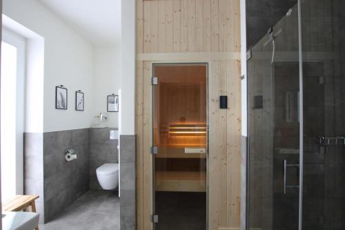 a bathroom with a toilet and a glass shower at Sonnengarten 3 - KüstenART in Kellenhusen