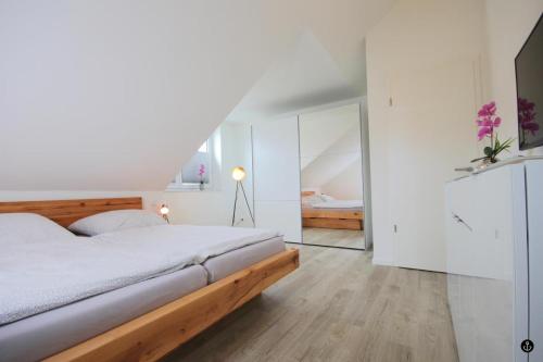 a white bedroom with a bed and a mirror at Sonnengarten 11 in Kellenhusen