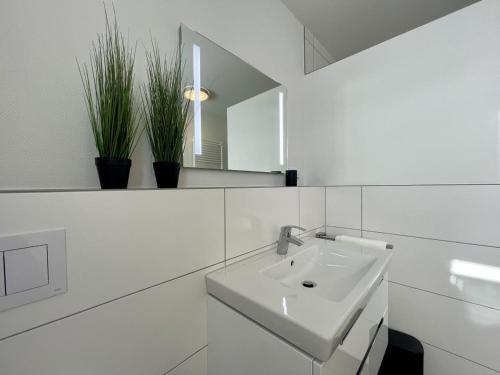 a white bathroom with a sink and a mirror at Dahmer Strand 7 in Dahme