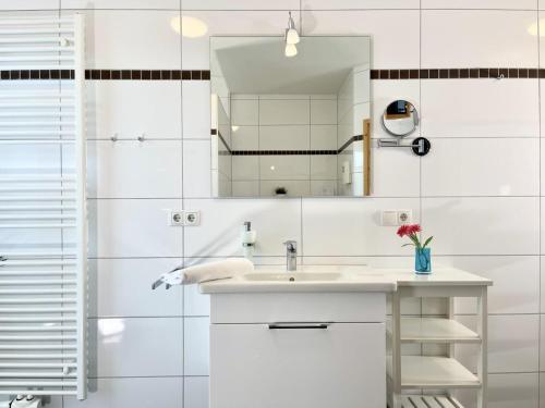 W białej łazience znajduje się umywalka i lustro. w obiekcie Quartier Hohe Geest 22 w mieście Cuxhaven