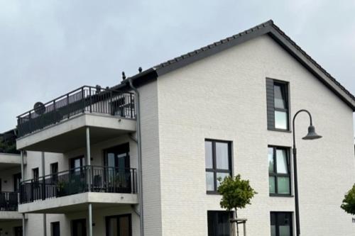 ein weißes Gebäude mit Balkon und Straßenbeleuchtung in der Unterkunft Neue Liebe Haffkrug 4 in Haffkrug