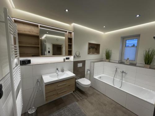 ein Badezimmer mit einer Badewanne, einem WC und einem Waschbecken in der Unterkunft Sonnenweg 31 - HAUS DIEMELSEE in Heringhausen