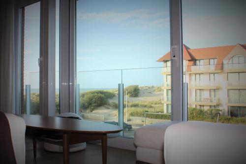 a room with a large window with a couch and a table at Boutique appartment with vue on sea and dunes in Koksijde