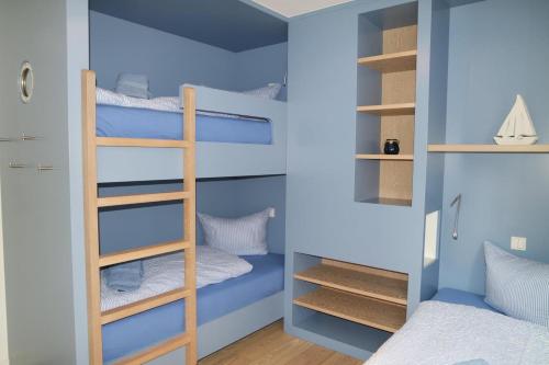 a bunk bed room with blue walls and bunk beds at Strandperle im Achterhus in Juist