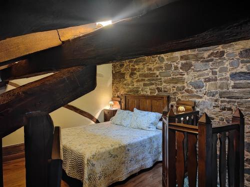 a bedroom with a bed and a stone wall at Apartamentos rurales Casa Do Cabo in Vega de Logares