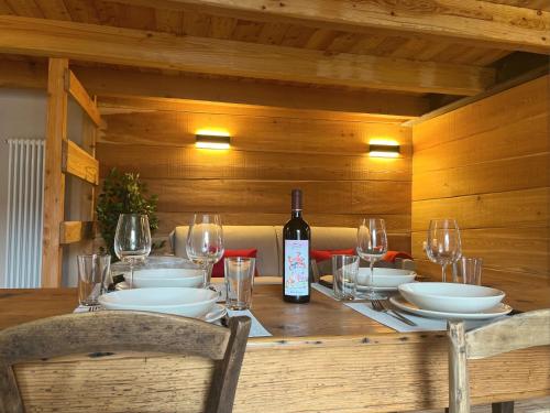 a wooden table with a bottle of wine and glasses at Baita La Pesse - Ad un passo dalle stelle in Nus