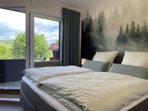 a bedroom with a large bed and a large window at Diemelblick 2 - TINNA in Heringhausen