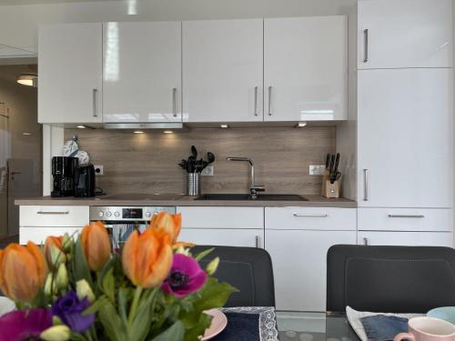 a kitchen with white cabinets and a table with flowers at Am Kutterhafen 24 in Fedderwardersiel