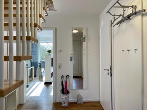 a hallway with white walls and a door with umbrellas at Am Kutterhafen 24 in Fedderwardersiel