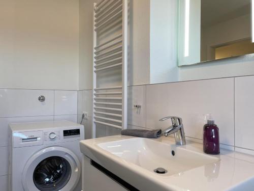 ein weißes Badezimmer mit einer Waschmaschine und einem Waschbecken in der Unterkunft Hansehaus 6 in Grömitz