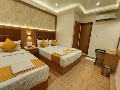 a hotel room with two beds and a desk at Hotel Riva International Goregaon- Near NESCO in Mumbai