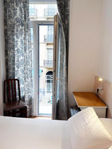 a bedroom with a bed and a door to a window at Pensión Régil in Donostia-San Sebastián