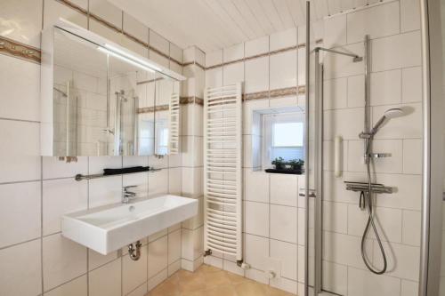 uma casa de banho branca com um lavatório e um chuveiro em Deichquartier em Oesterdeichstrich