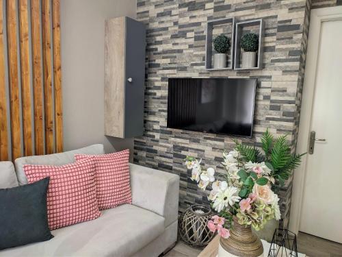a living room with a couch and a tv on a brick wall at Pietra di Luna 1 in Kriopigi