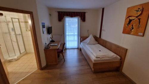 a bedroom with a bed and a desk and a door at Landgasthaus Jägerhof in Absberg