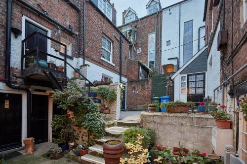 an alley with a bunch of potted plants and buildings at Seashell Cottage in Whitby