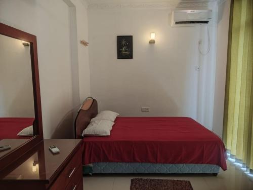 1 dormitorio con 1 cama con manta roja y espejo en Beach view luxury apartment, en Karagampitiya