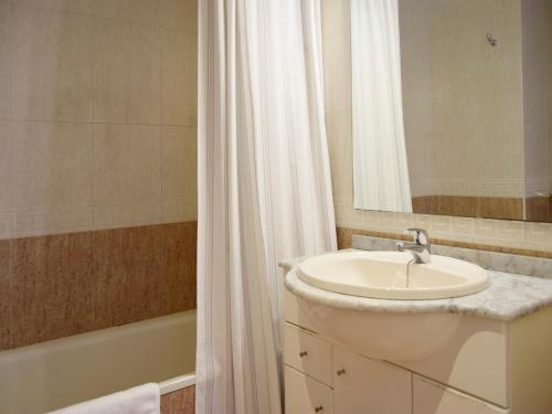 y baño con lavabo, espejo y bañera. en Apartamentos El Pilar Suites 3000 en Zaragoza