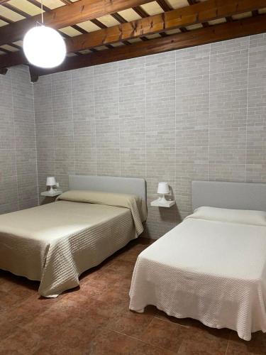 two beds in a room with two lamps on the wall at Casa Rural El Almendrillo in Arcos de la Frontera