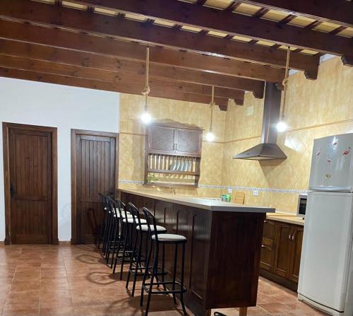 a kitchen with a bar with stools and a refrigerator at Casa Rural El Almendrillo in Arcos de la Frontera