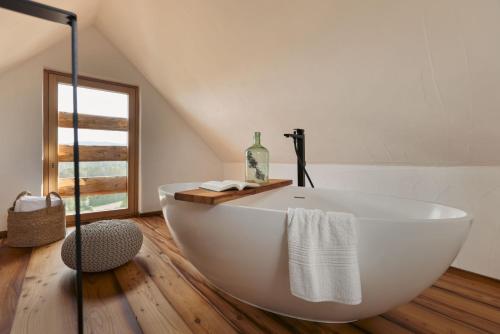 a white bath tub in a bathroom with a window at AM WILDBACHBERG Luxus Ferienhäuser mit Infinitypool, Weinkeller und Privatsauna in Deutschlandsberg