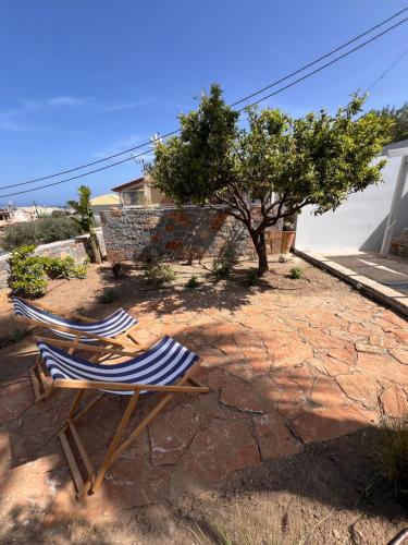 two lawn chairs and a tree in a yard at Gioma Garden Villas in Istron