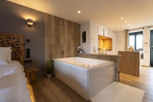 a bedroom with a large white bath tub next to a bed at La Suite SPA privatif du Moulin in Saint-Laurent-dʼAndenay