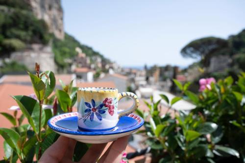 a person holding a coffee cup on a plate at Valle d'Amalfi Suites in Amalfi
