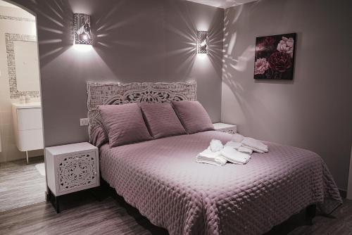 - une chambre avec un lit violet et des serviettes dans l'établissement VILLAS BEAUMONT avec piscine et jacuzzi proche D'UZES ET ANDUZE, à Cannes-et-Clairan