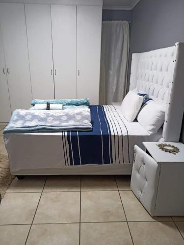 1 dormitorio con cama blanca y manta azul en WAMPEX GUEST HOUSE POTCHESTROOM, en Potchefstroom