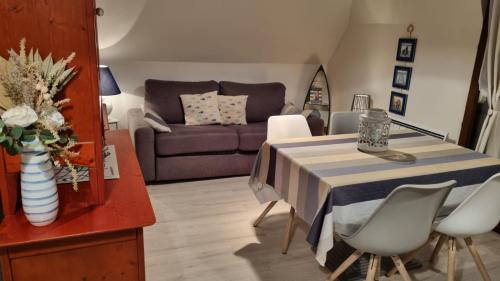 ein Wohnzimmer mit einem Tisch und einem Sofa in der Unterkunft Appartement Clos Mathilde in Cabourg