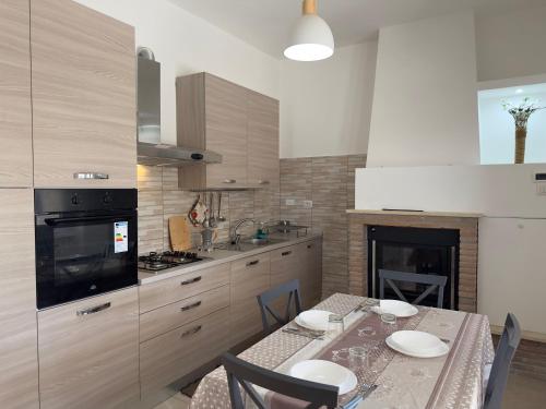 eine Küche mit einem Tisch mit Stühlen und einem Kamin in der Unterkunft 110 mq piano terra- Parcheggio privato-Giardino in Velletri