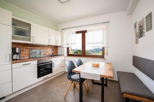 a kitchen with white cabinets and a table and chairs at Am Pön - Ferienwohnungen in Medebach