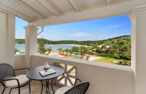 a balcony with a table and chairs and a view of the water at Bella Mare Hotel in Kassiopi
